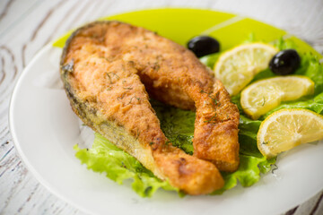 piece of fried salmon fish in a plate with lemon
