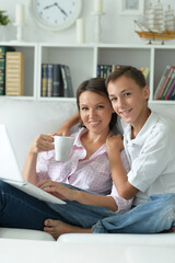 Mother and son using modern laptop at home