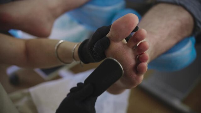 Pedicure procedure - the master polishes the harsh skin of her client after a salt bath using an emery board