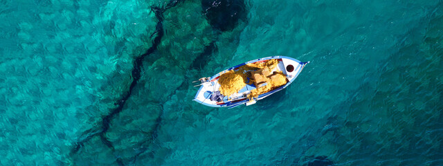 Plakat Aerial drone top view ultra wide panoramic photo of traditional wooden fishing boat anchored in crystal clear turquoise sea of Antipaxos island, Ionian sea, Greece