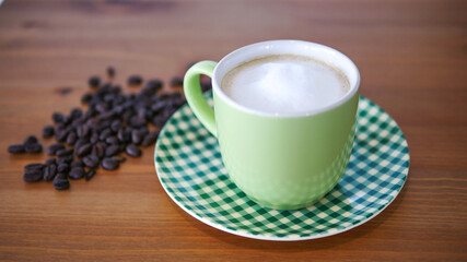 A green cup of Cappuccino with frothy foam and coffee bean on wood background
