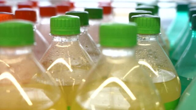 close-up on a store shelf a row of plastic bottles with different colored soda