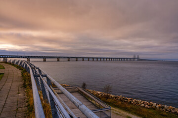 Fototapeta premium The Sound Bridge, the bridge and underwater tunnel connecting Malmo, Sweden with Copenhagen, Denmark. Beautiful sunset sky in the background