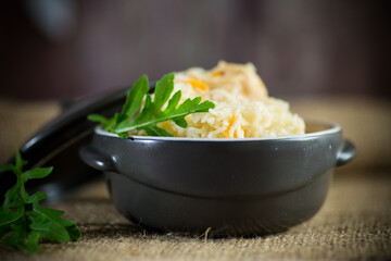 boiled rice with vegetables and meat in a ceramic bowl on a wooden table