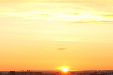 Sun below the horizon and clouds in the fiery dramatic orange sky at sunset or dawn backlit by the sun. Place for text and design