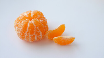 Peeled whole tangerine and two tangerine slices isolated on white background. Vitamins. Place for your text. Selective focus.