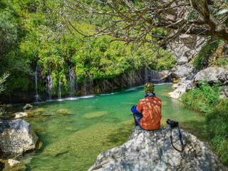 waterfall flowing in nature, a man sitting on a stone, a waterfall, a waterfall among the rocks. Hakkari in Turkey
