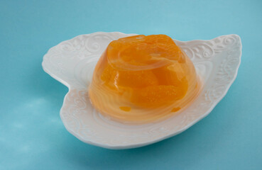 A plate of delicious orange fruit jelly isolated on a blue background