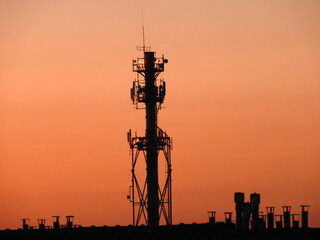 Komin ciepłowni miejskiej na tle nieba przed zachodem słońca.