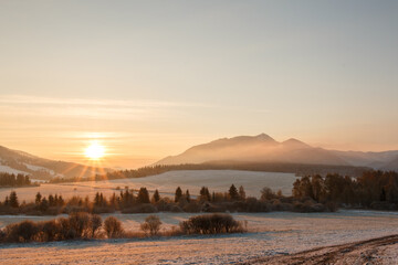 Sunrise over the mountains and snow covered field