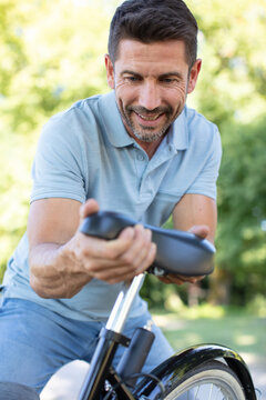 Mature Male Cyclist Adjusting Bicycle Seat