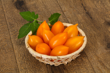 Yellow tomato heap in the wooden bowl
