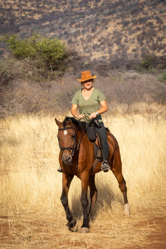 Blonde horsewoman rides towards camera in savannah
