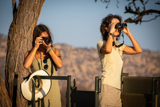 Brunettes with camera and binoculars in jeep