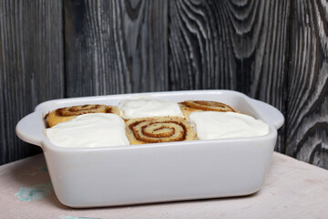 Baking cinnabons. The cinnamon rolls is in the baking dish. Background from black pine boards. Close-up shot.