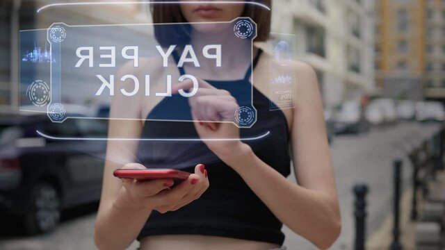 Unrecognizable young adult woman standing on the street interacts HUD hologram with text Pay per click. Girl in black clothes uses technology of the future mobile screen