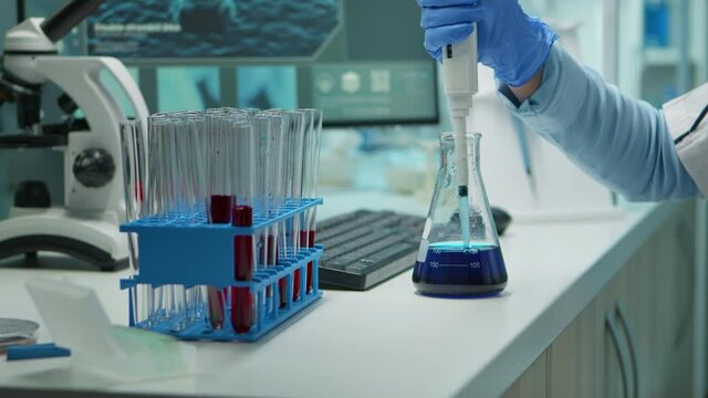 Close up of scientis testing liquid sample late at night using micropipette for medical treatment in laboratory. Team examining virus evolution using high tech for vaccine development against covid19