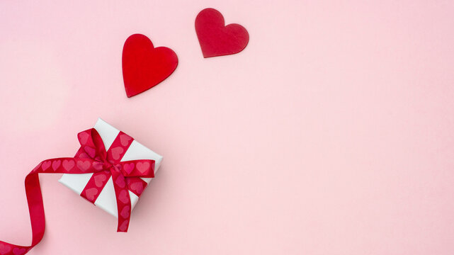 Gift box with a red ribbon and shape of heart top view on the pink Valentines day background, copy space