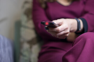 A television control panel in the hands of a girl.