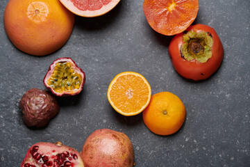 Orange, grapefruit, pomegranate, passion fruit and kaki on dark grey background