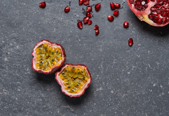 Colourful passion fruit isolated with pomegranate on dark grey stone background.