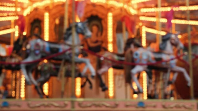 Blurry background carousel with horses lots of golden lights in the evening. a holiday concept with kids or romantic Valentine's Day outing. Carousel vintage on the square