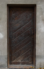 Old wooden door with a wrought iron handle in the side gate leading to the garden in the courtyard of the convent
