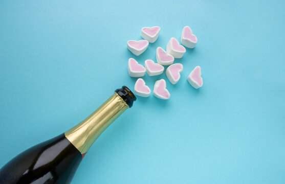 An open bottle of champagne and hearts on a blue background. Holiday concept, New year, Valentine's Day, March 8.