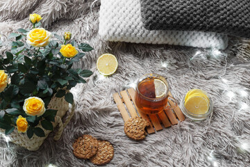 Obraz na płótnie Canvas Cup of tea with lemon, wicker basket with yellow roses