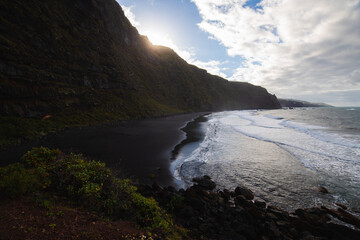 volcanic sand beach and cliffs