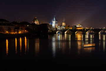 Fototapeta na wymiar Scenic view of illuminated Prague skyline at night. Charles bridge, Klementinum and National Theater and reflections in Vltava river