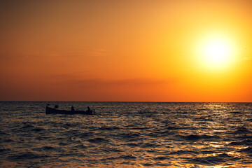 Fototapeta na wymiar Fisherman sailling with his boat on beautiful sunrise over the sea