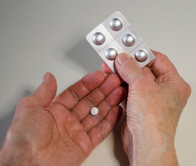 Close-up of female hands holding a blister pack with pills. Elderly woman takes medication.