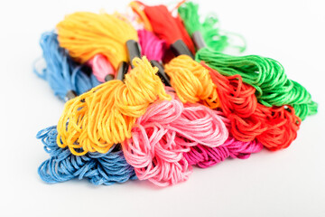 Many mixed vivid colored sewing threads for embroidery isolated on a white table, top view or flat lay of red, pink, yellow, blue and green textile materials.
