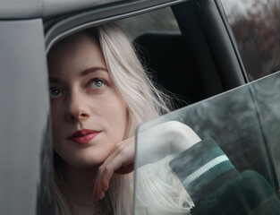 Fototapeta na wymiar Young blond woman sitting in the car vintage look dreaming thinking waiting road trip