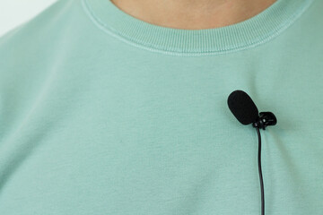 Small lavalier microphone or mic buttonhole on a man's t-shirt closeup