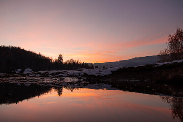 Amazing mountain sunset with reflection in the lake in winter