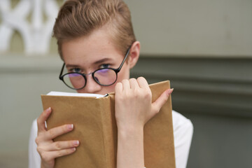 female student with glasses with a book in her hands Near the Institute building