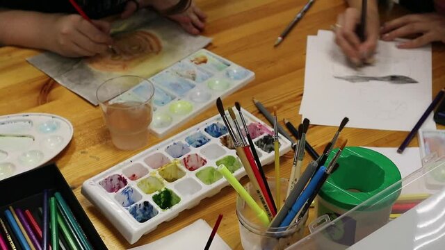 Paints, brushes and albums on the table. Shooting drawing top view