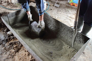 Two male workers mix cement mortar with shovels and bucket in a large basin close up, manual labor...