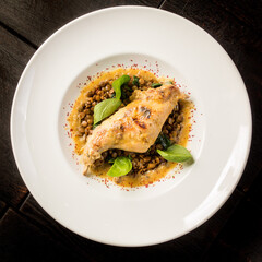 Stewed rabbit leg with lentils on a large round plate