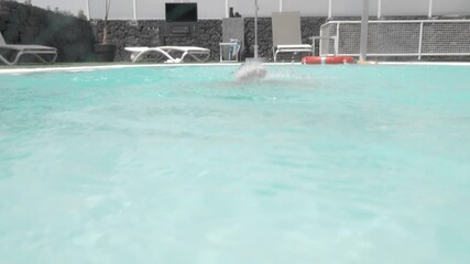 Boy improving his diving skills and practising in the swimming pool. He throwing toys into water and getting them from the pool bottom