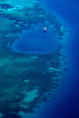 White yacht floating above a coral reef in beautiful bay. Aerial view