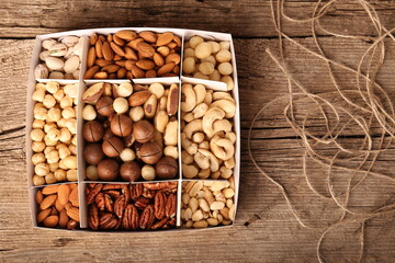 Different grade of nuts in a box on a wooden background top view