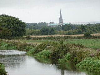Fototapeta na wymiar The canal, vegetation and the cathedral in the distance