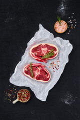 Raw rack of lamb on wooden cutting board with herbs and seasoning