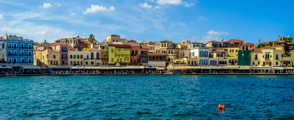 Fototapeta na wymiar A panorama view of the mulit-coloured restaurants and bars in the harbour bay of Chania, Crete on a bright sunny day
