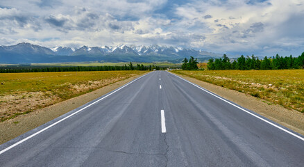 highway stretching into the distance to the mountains with snowy peaks