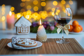 festive Christmas mood with a glass of wine and a burning candle on the kitchen dinner table