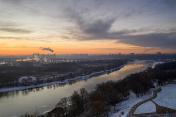 panoramic view of the park in the city on the river bank with old buildings at sunrise in winter filmed from a drone